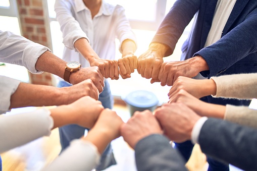 Group of business workers standing bumping fists at the office